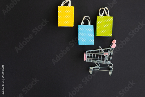 Small paper shopping bags with shopping cart on black background
