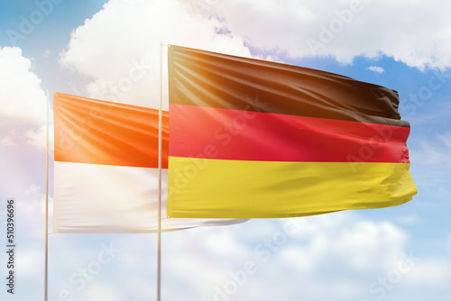 Sunny blue sky and flags of germany and indonesia