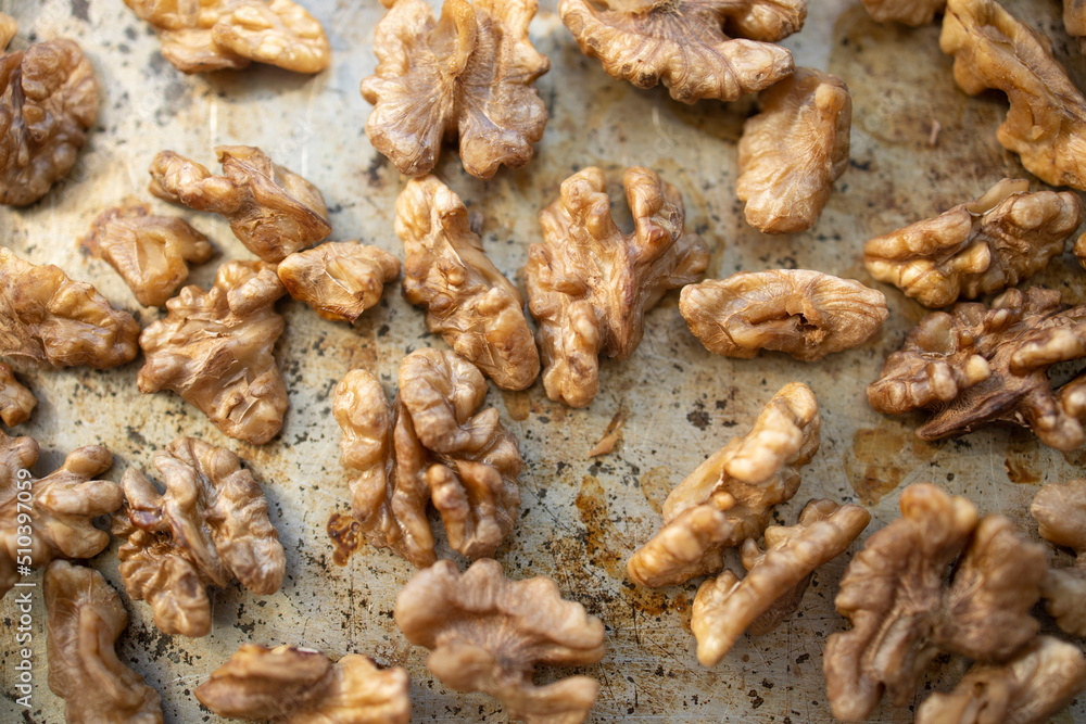 Roasted walnut lies on a metal baking sheet. Protein, healthy nuts, shortage of walnuts, more expensive snacks. Roasted walnut lies on a metal baking sheet. Protein, healthy nuts, shortage of walnuts, more expensive snacks.