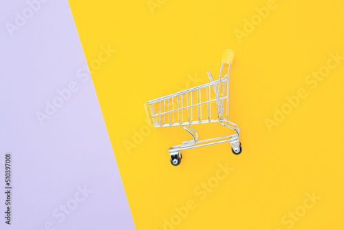 Mini supermarket trolley on violet yellow background