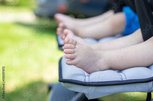 twins babies feet,nature background.close up of toddlers legs.little cute toes and feet of boy and girl sitting outdoors,park,in a trolley for two.brother and sister,maternity,mother of two.