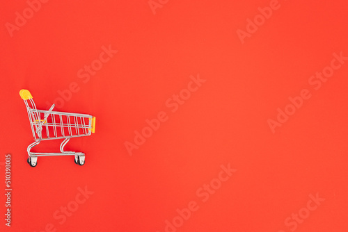 Mini shopping trolley on red background