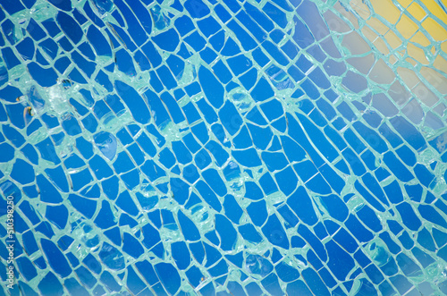 Detail of a broken glass of a blue paddle tennis court, background out of focus.