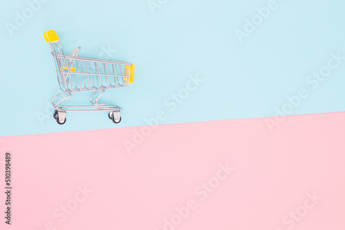 Consumer concept, mini shopping trolley for shopping on a colored background, minimalism, top view..