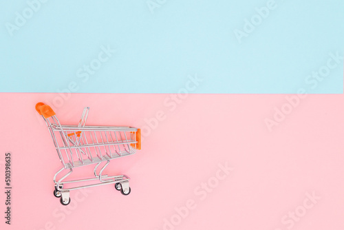 Consumer concept, mini shopping trolley for shopping on a colored background, minimalism, top view..
