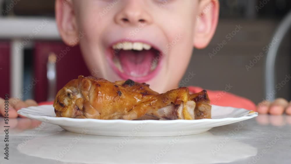 funny caucasian boy 7-8 years old hungry take off plate crispy fried chicken legs.child eat fried chicken meat.delicious grilled chicken dinner