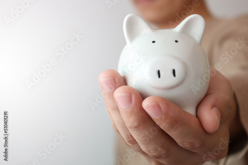 Fotografie Man holding piggy bank carefully, saving money for retirement concept