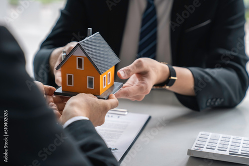 Real estate agent, Asian businessman handing model houses to customers, Real estate trading ideas, and bank loans for buying and selling houses and land.