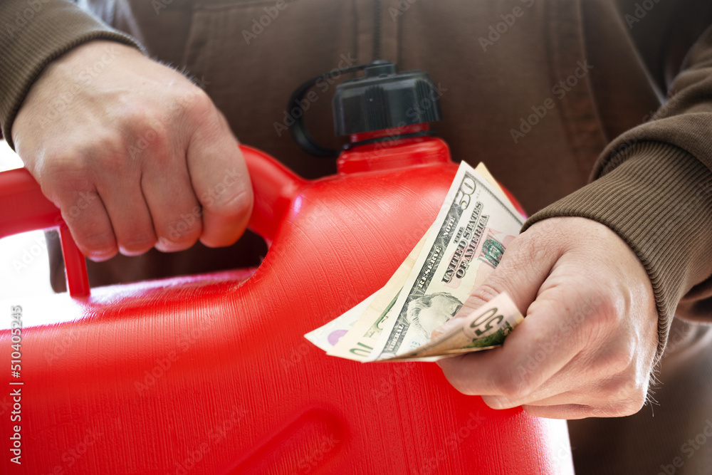 Man holds red jerry fuel can and dollar bills