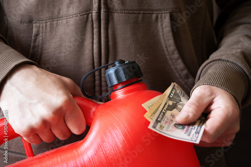 Man holds red jerry fuel can and dollar bills