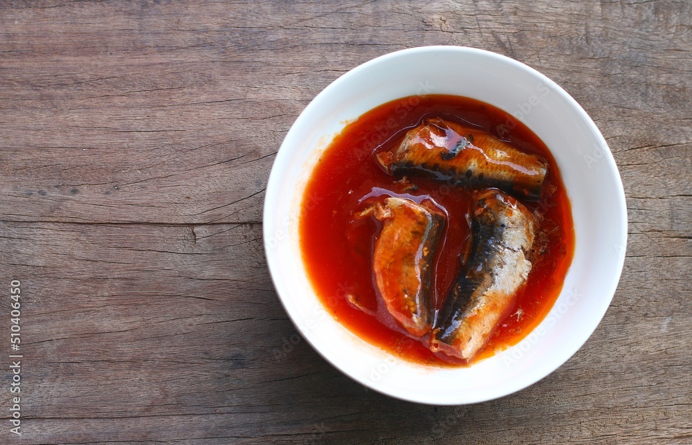 Canned fish with tomato sauce in a white cup is placed on the table, canned fish is a readymade