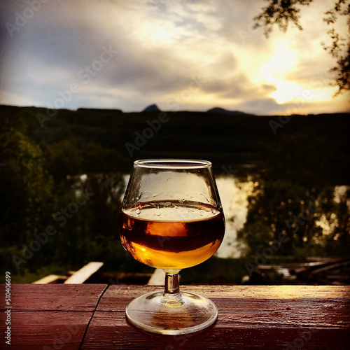Glass with Cognac / Whiskey on Rustic Handrail at Nighttime