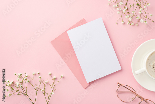 Business concept. Top view photo of workspace cup of hot drinking on saucer stylish glasses envelope paper card and white gypsophila flowers on isolated pastel pink background with blank space © ActionGP