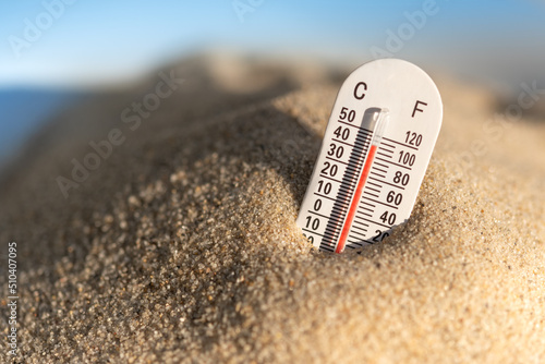 Weather thermometer with high temperature outdoors in the sand photo