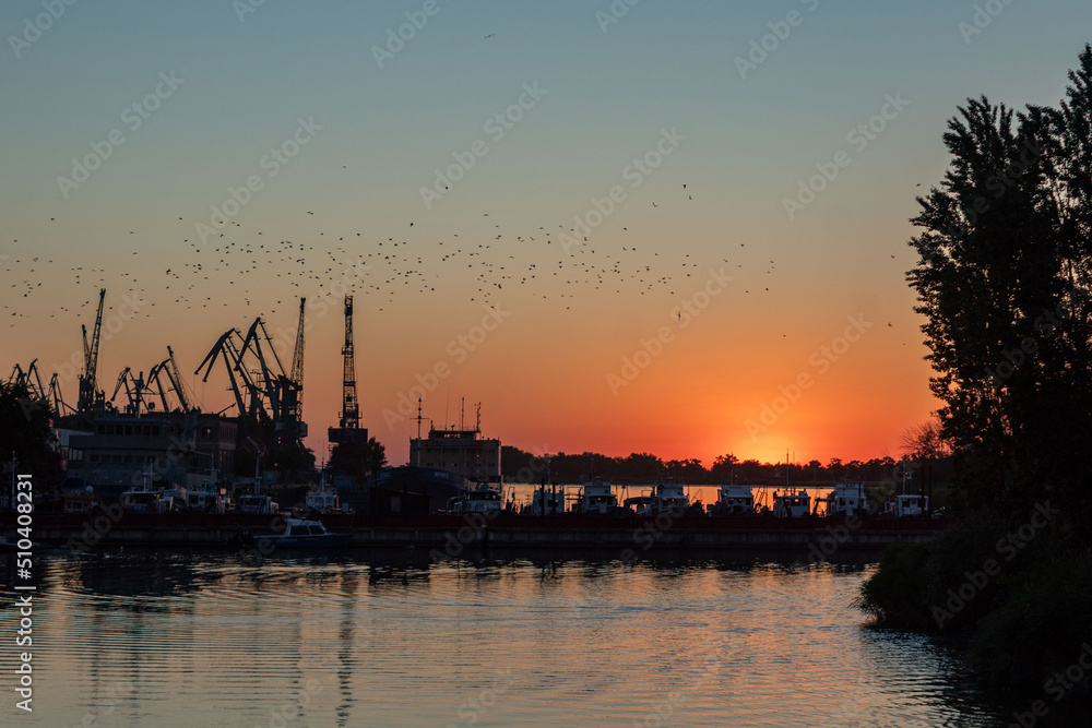 Sunset in the port, cranes in the backlight.