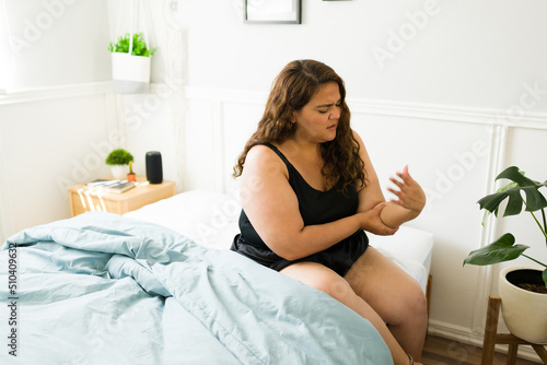 Sad fat woman having a cramp in her arm