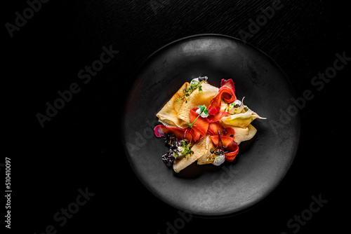 Fototapeta Naklejka Na Ścianę i Meble -  Crepes with smoked gravlax salmon on black plate on wooden table dark background