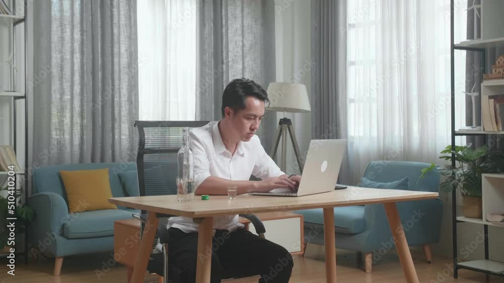 Asian Man Drinking Vodka While Typing On A Laptop At Home
Asian Man Drinking Vodka While Typing On A Laptop At Home