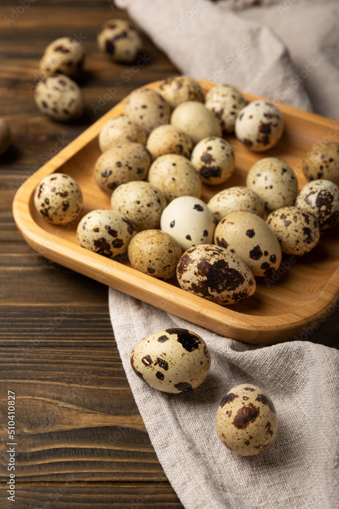 Quail eggs in a bamboo plate on a brown texture background.Organic food. Place for text. fresh eggs Quail eggs in a bamboo plate on a brown texture background.Organic food. Place for text. fresh eggs