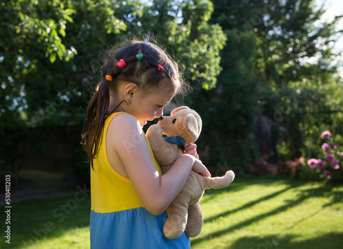 cute girl of 6-7 years old plays nose to nose with her plush dog. Child on a walk in the park on a sunny summer day. Summer mood, happy childhood. Favorite toy, tendern photo