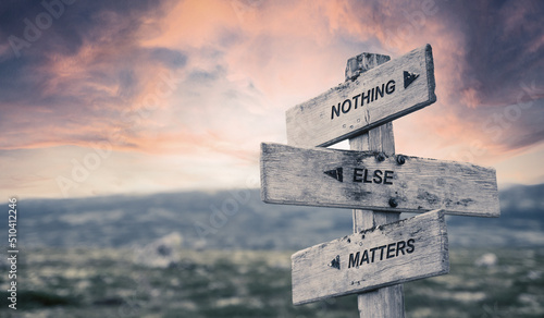 nothing else matters text quote caption on wooden signpost outdoors in nature with dramatic sunset skies. Panorama crop.