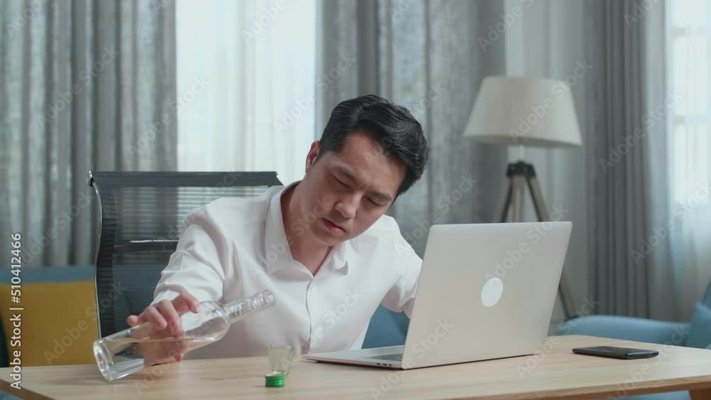 Asian Man Pouring Vodka In A Shot Glass Before Drinking And Typing On A Laptop At Thome
Asian Man Pouring Vodka In A Shot Glass Before Drinking And Typing On A Laptop At Thome