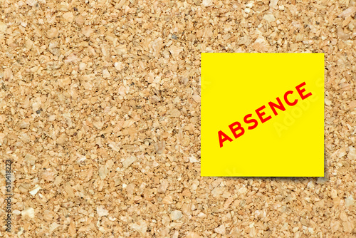 Yellow note paper with word absence on cork board background with copy space