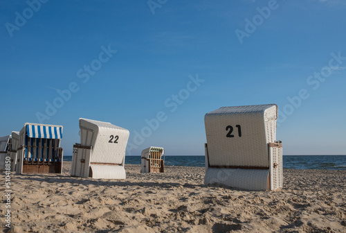 Fototapeta Naklejka Na Ścianę i Meble -  Strandkorb providing shelter from sun and wind. Hooded Wicker beach chairs on a beach at the baltic sea in Bansin, Usedom, Germany