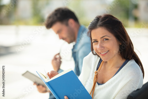 female waiting for transport while reading a book