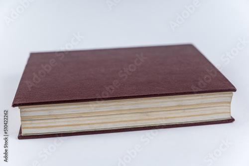 The large red book against a neutral background. Closed book with yellowed pages. Hardcover encyclopedia. Close-up. Selective Focus.