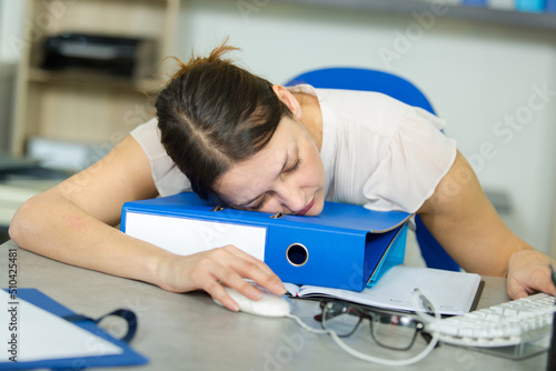 woman asleep at her desk hand still on the mouse photo