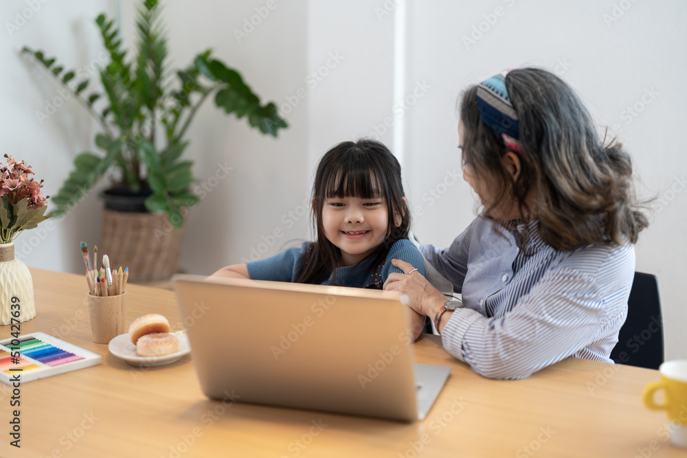 Little girl with grandmother using laptop computer, e learning on virtual online class at home. Little girl with grandmother using laptop computer, e learning on virtual online class at home.