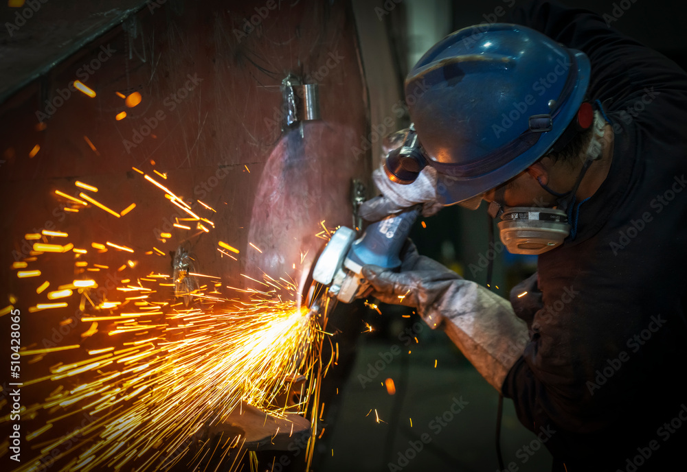 The worker polished the metal splashing sparks The worker polished the metal splashing sparks