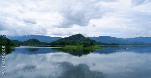 An island in the middle of the beautiful Lake Malahayu. The lake view is blue and green. There are several fishing boats and the weather is cloudy.