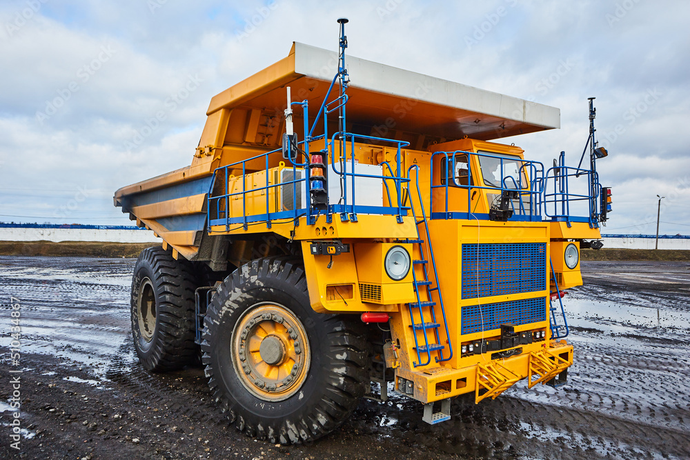 A quarry yellow dump truck operates on an open-pit mining site