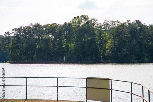 the gorgeous blue rippling waters of Lake Acworth with a long winding footpath around the lake surrounded by a metal rail and lush green trees, grass and plants at Proctor Landing Park in Acworth photo