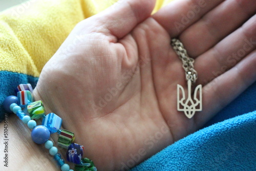 Ukrainian woman  holds a pendant in the form of the coat of arms of Ukraine in her hand