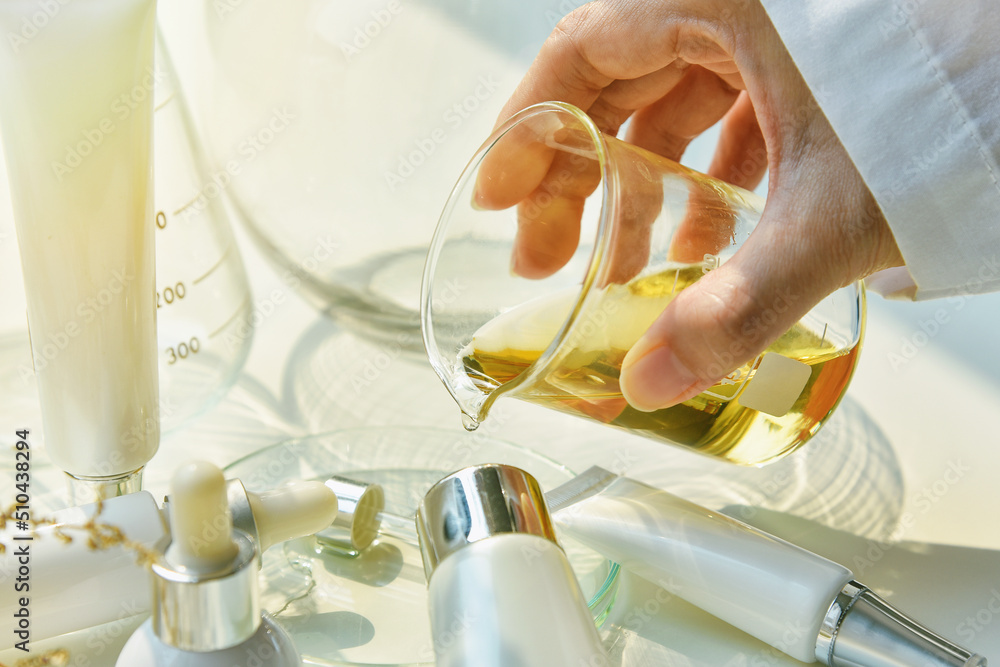 Scientist mixing natural skin care beauty products, Organic botany extraction and scientific laboratory glassware, Blank label cosmetic container for branding mock-up.