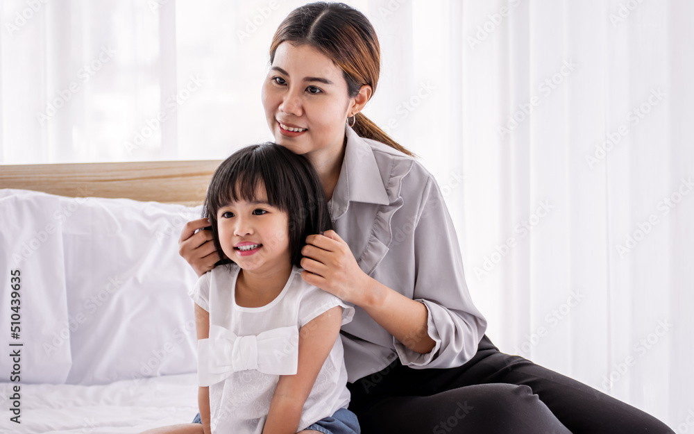 Portrait Asian warm family, mother, daughter playing together, hugging on white bed in comfortable bedroom at home with love and fun, smiling with happiness. Lifestyle, Education and Kid Concept. Portrait Asian warm family, mother, daughter playing together, hugging on white bed in comfortable bedroom at home with love and fun, smiling with happiness. Lifestyle, Education and Kid Concept.