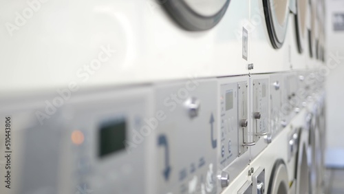 Slika na platnu Row of washing and drying machines, public coin laundry in California, USA
