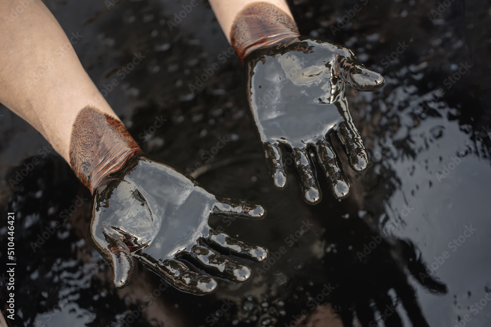 Crude oil in hand due to a crude oil leak. Caucasian hands covered with