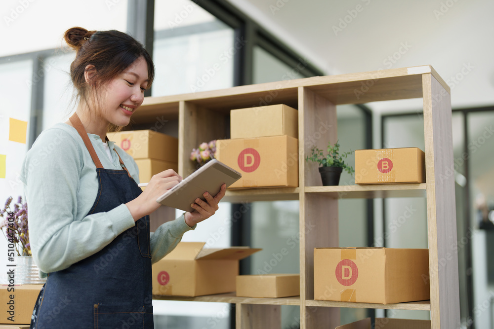 A portrait of a small startup, an SME owner, an Asian female entrepreneur checking orders to arrange the produce before packing the products in the inner boxes with the customers. Freelance concepts
