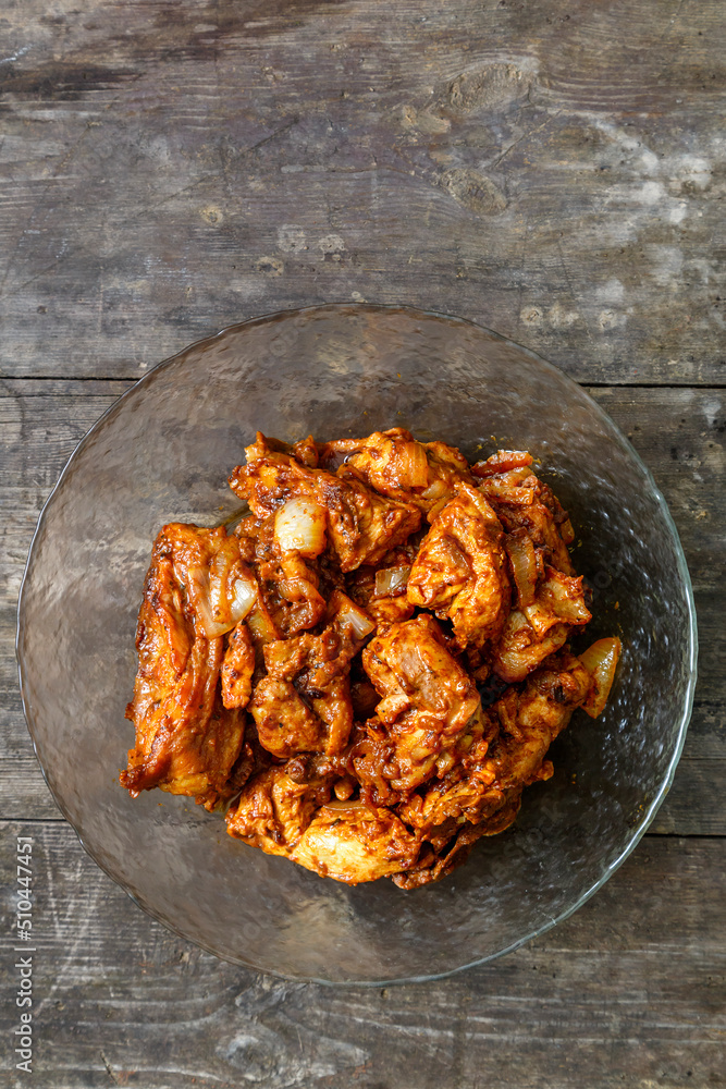 Pieces of chicken in sauce fried in a glass plate on a dark wooden table. Pieces of chicken in sauce fried in a glass plate on a dark wooden table.