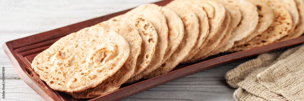 Homemade Indian Traditional Flatbread called Chapati on a white wooden background. Baked indian flatbread. Indian