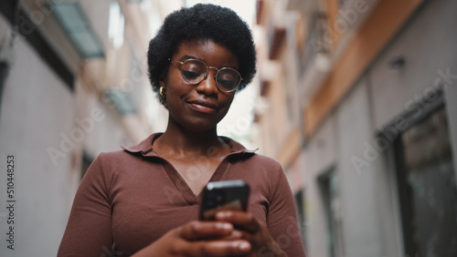 Young Afro girl wearing glasses texting on a smartphone. Female