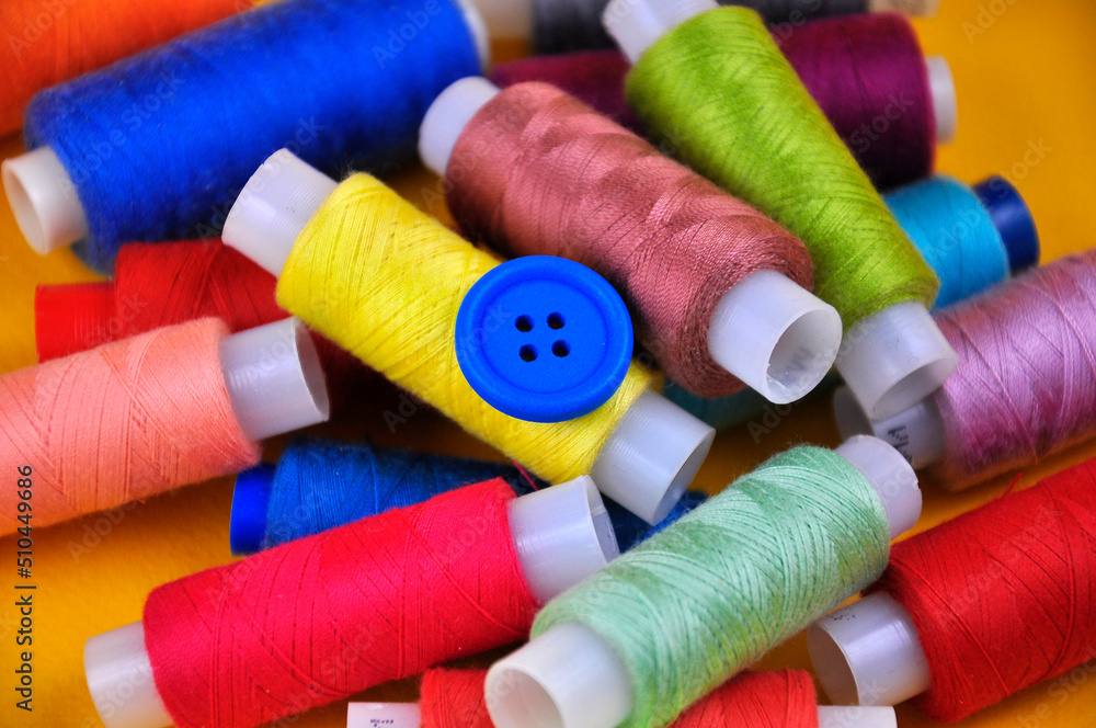 Set of multicolored buttons and Spools threads on a yellow background. Blurring. Set of multicolored buttons and Spools threads on a yellow background. Blurring.