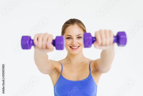 Beautiful young woman doing fitness exercise with dumbbells on white background