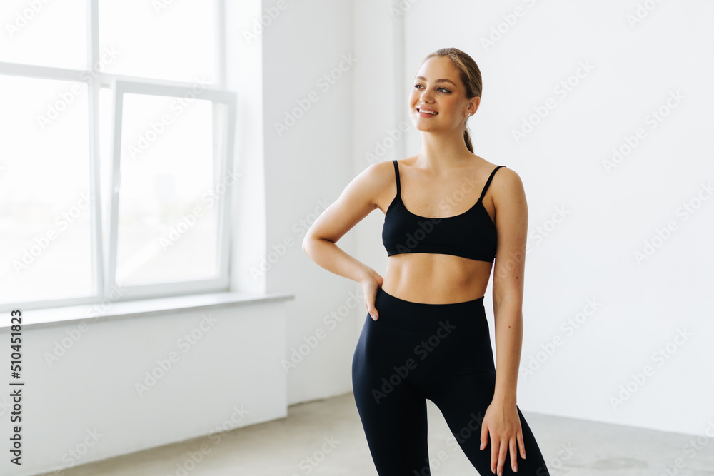 Beautiful young woman with natural make-up and gathered hair, dressed in a gray sports uniform. Advertising sportswear and yoga wear. Healthy lifestyle, sport