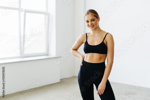 Young fitness woman in sport style standing at gym