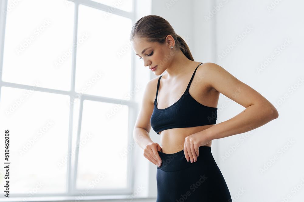 Beautiful young woman with natural make-up and gathered hair, dressed in a gray sports uniform. Advertising sportswear and yoga wear. Healthy lifestyle, sport Beautiful young woman with natural make-up and gathered hair, dressed in a gray sports uniform. Advertising sportswear and yoga wear. Healthy lifestyle, sport